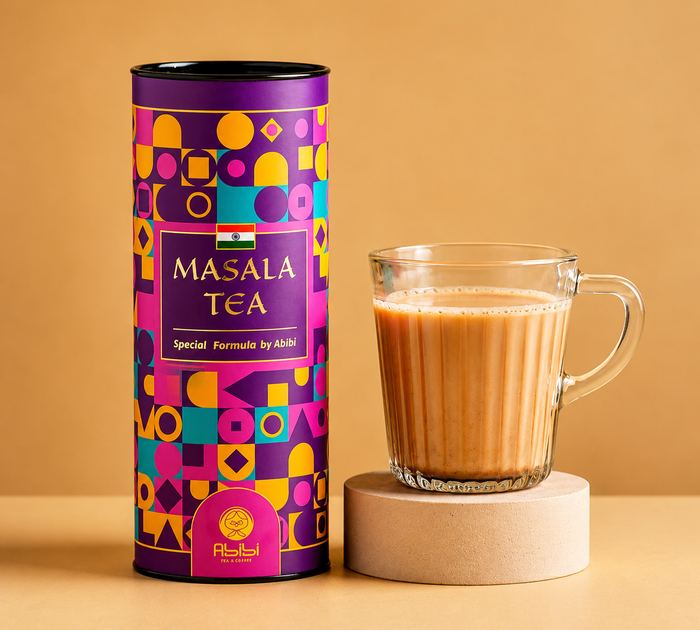 Colorful canister of Masala Tea next to a glass of tea on a beige background