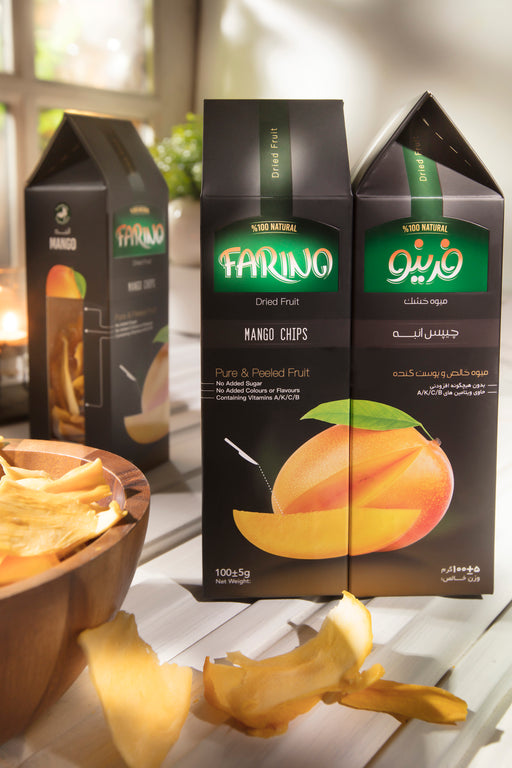 Two boxes of Farina Mango Chips on a table with a bowl of chips and mangoes.