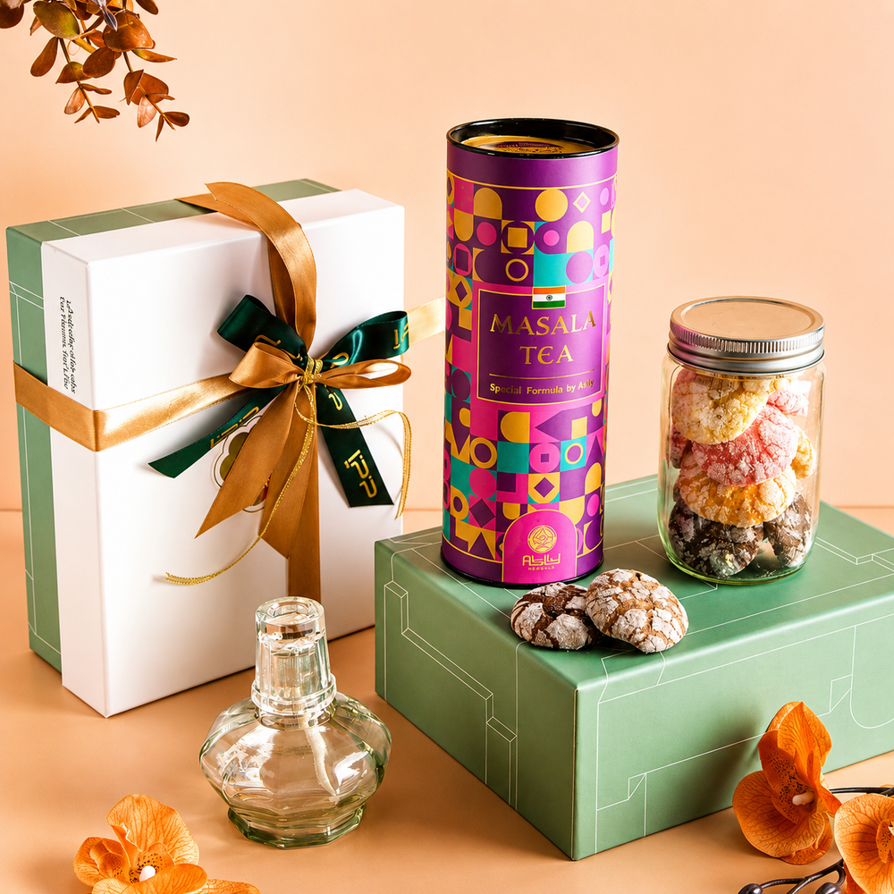 Gift box with ribbon, Masala Tea canister, jar of cookies, and decorative items on a peach background