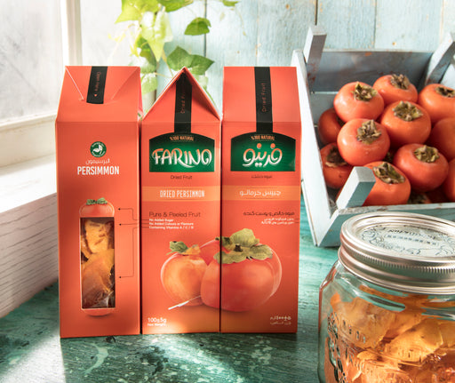 Three boxes of Farino persimmon products on a table with persimmons and a jar in the background.